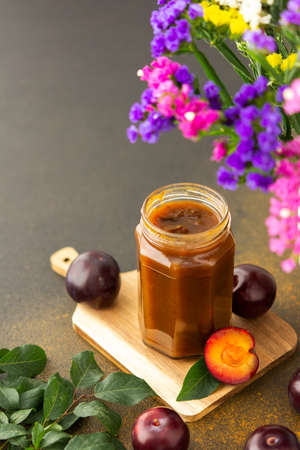 Homemade plum jam in a jar on a board with fresh plums, harvesting for the winterの写真素材