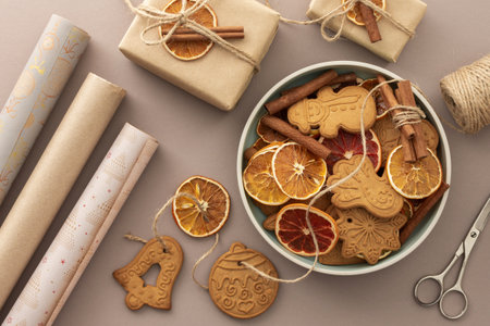 Preparing to decorate your home for Christmas, gift paper and dry citrus fruits with gingerbread cookies on a pastel powdery backgroundの写真素材