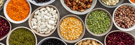 Banner of different types of legumes in bowls, green with yellow peas and mung beans, chickpeas and peanuts, colored beans and lentils, top viewの写真素材