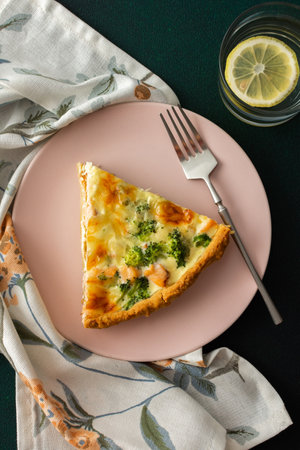 Homemade pie with red fish and broccoli, quiche with salmon and char, cheese and cream, portion of pie on a plateの写真素材