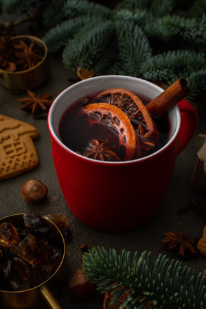 Christmas hot alcoholic drink mulled wine in a mug with citruses, aromatic spices and cinnamon among the spruce branchesの写真素材