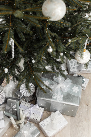 White and silver gift boxes with bows under the Christmas tree and snow, Merry Christmas and Happy New Yearの写真素材