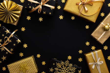 Golden and black gift boxes with bows and snowflakes and snow on a black background, Merry Christmas and Happy New Yearの写真素材