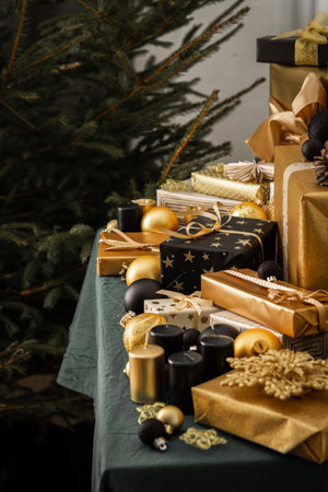 Preparations for the holiday, for dressing the Christmas tree, black and gold gifts and Christmas toys and decorations on the table near the fir treeの写真素材