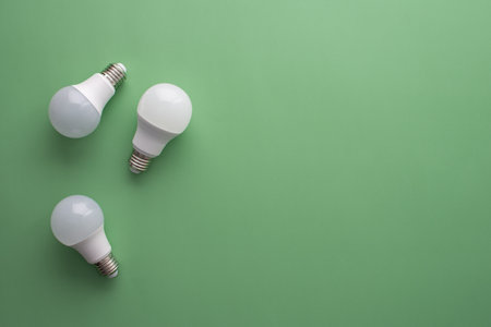 Save energy, accounting and saving money, energy saving light bulbs on green background, money spending planning, rising electricity costsの写真素材