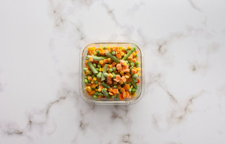 Frozen mix of vegetables in a container close-up, frozen asparagus beans and peas, corn and carrots, copy space, top viewの写真素材