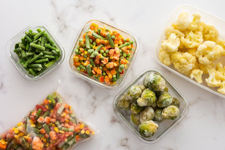 Frozen vegetables in containers and bags, frozen cauliflower and asparagus beans, peas and corn, Brussels sprouts and carrots, mix of vegetables, top view, copy spaceの写真素材