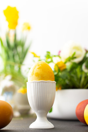 Easter interior, yellow Easter egg close-up on the background of flowers and cute rabbitsの写真素材