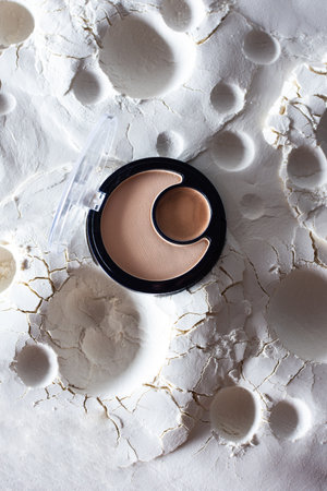 Crescent shaped face powder and round eye shadows, cosmetics on abstract lunar surface, makeup, top viewの写真素材