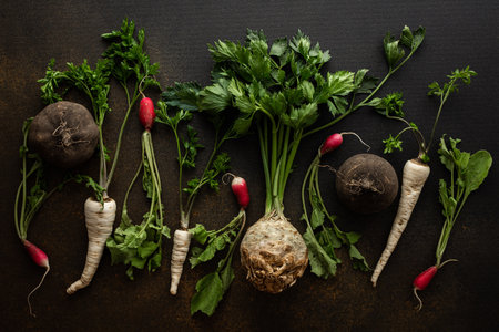 Parsley and selera roots with tops, black and red radish close-up on a brown background, top view, healthy autumn seasonal roots, copy spaceの写真素材