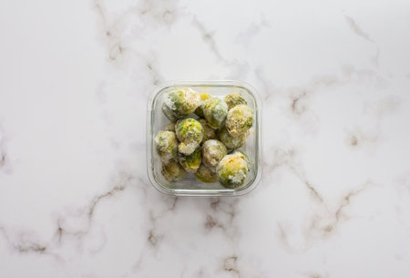 Frozen brussels sprouts in container close up, copy space, top viewの写真素材