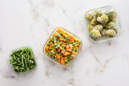 Frozen vegetables in containers , frozen cauliflower and asparagus beans, peas and corn, Brussels sprouts and carrots, mix of vegetables, top view, copy spaceの写真素材