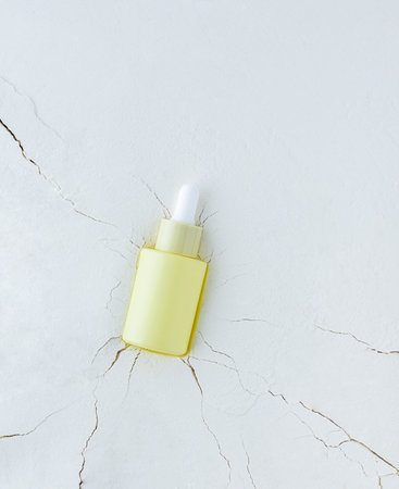 Moisturizing serum in a bottle with a pipette on an abstract background with cracks, hyaluronic...