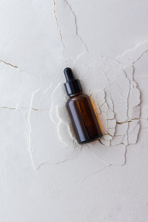 Moisturizing serum in a bottle with a pipette on an abstract background with cracks, hyaluronic serum or toner or lotion, face and body skin careの写真素材