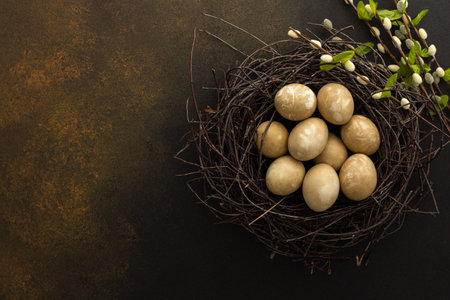 Colorful Easter eggs in a nest with willow branches on a brown background, top view, copy spaceの写真素材
