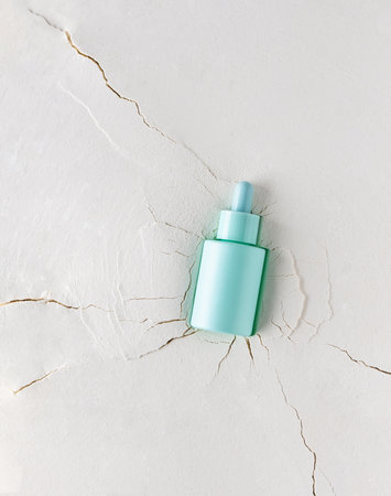 Moisturizing serum in a bottle with a pipette on an abstract background with cracks, hyaluronic serum or toner or lotion, face and body skin careの写真素材