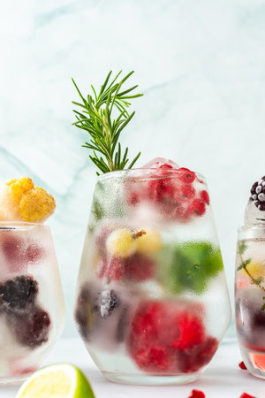 Refreshing drink with ice cubes with fruits and citrus fruits in a glass, ice with blackberries and raspberries, gooseberries and currants, with mintの写真素材
