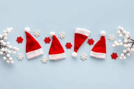 Santa Claus hats and snowflakes and rowan branches on a blue background, Christmas background, Merry Christmas and Happy New Year concept, top view, copy spaceの写真素材