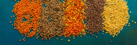 Multi-colored lentils on an emerald green background, scattered yellow and brown, green and orange...