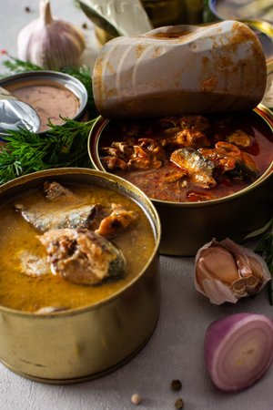 Different open tin cans with canned fish among spices and herbs, canned salmon and mackerel, sprat and sardine, tuna and herring and fish pateの写真素材