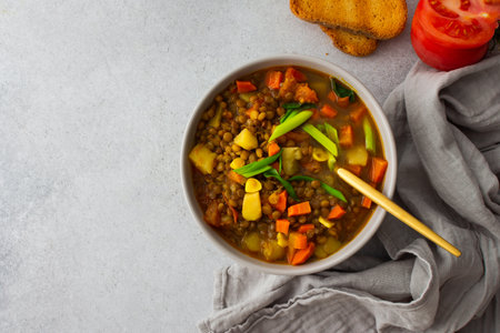 Healthy vegetarian lunches, brown lentil soup with tomatoes and carrots, green onions, potatoes and curry spices, toasted croutons, top viewの写真素材