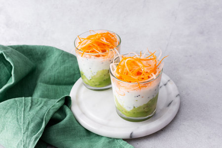 Healthy breakfasts and lunches, avocado and yogurt with chia, grated carrots and radishes in glass cupsの写真素材