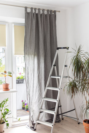 Stepladder near the window to hang curtains, spring cleaning in the apartment, sewing curtains and services for hanging themの写真素材