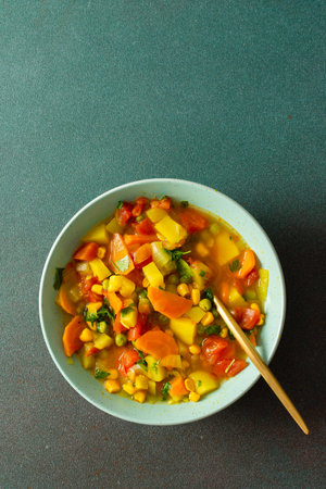 Minestrone soup from zucchini and tomato, onion and carrots, corn and peas with parsley, a plate of soup close-up, vegetarian soupの写真素材
