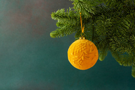 Christmas golden ball hanging on a fir branch on a green background , Christmas backgroundの写真素材