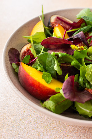 Salad with mixed lettuce and peaches with figs, plate with salad on beige backgroundの写真素材