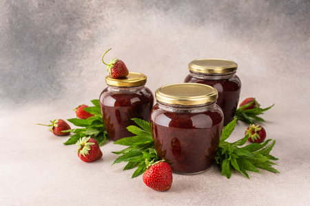 Homemade summer preservation, strawberry jam in jars, jars with jam and mint leaves and fresh strawberriesの写真素材