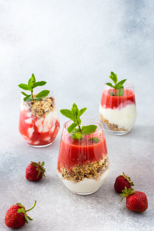 Healthy tasty breakfasts, glasses with granola and yogurt and strawberry smoothieの写真素材
