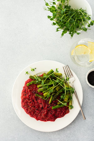 Beetroot risotto with rice and sesame seeds, baked asparagus with pea microgreensの写真素材