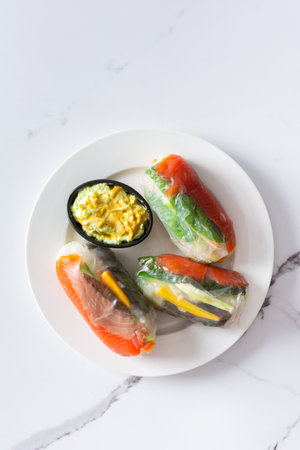 These traditional Vietnamese spring rolls feature rice paper filled with lettuce, salmon , carrots, and cucumber, served with fish sauce, offering a light and flavorful appetizerの写真素材