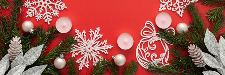 Red Christmas background with fir branches and pink Christmas tree toys and snowflakes and candles, bannerの写真素材
