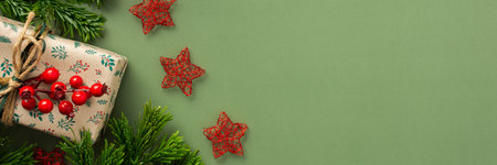 Christmas festive banner, fir branches and gift boxes with a sprig of rowan and red stars on a green background, top viewの写真素材