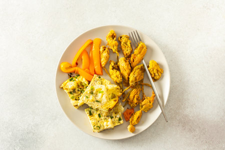 Savor the crispy fried zucchini flowers in batter, a savory cauliflower omelette with stewed peppers nutritious mealの写真素材