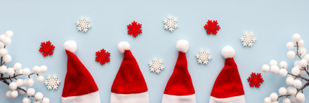 Santa Claus hats and snowflakes and rowan branches on a blue background, Christmas background, Merry Christmas and Happy New Year banner, top view, copy spaceの写真素材