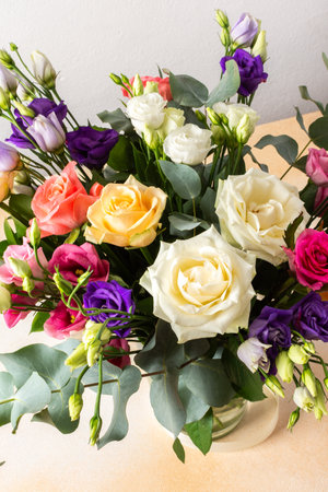 A beautiful bouquet of vibrant roses, eucalyptus, and delicate eustoma in white, pink, and purple hues, perfect for an anniversary or birthday celebrationの写真素材