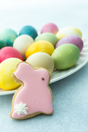 Multi-colored Easter eggs in an oval dish with decorative bunnies on a blue background, Happy Easter holidayの写真素材