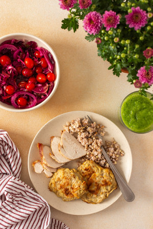 A healthy meal of green buckwheat with chicken breast, zucchini pancakes, fermented vegetable salads, celery cucumber smoothieの写真素材