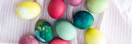 Multi-colored Easter eggs on a pink tablecloth, top view, Happy Easter holiday bannerの写真素材