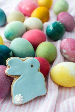 Multi-colored Easter eggs with decorative bunnies on a pink tablecloth, Happy Easter holidayの写真素材