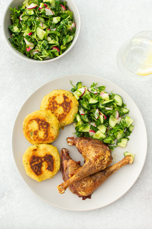 Chickpea cutlets with mixed salad with cucumbers and radishes, baked chicken legs, a delicious hearty lunch or dinnerの写真素材