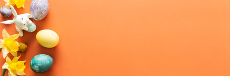 Top view of natural dyes dyed Easter eggs on orange background, yellow daffodils and bunnies, Happy Easter bannerの写真素材