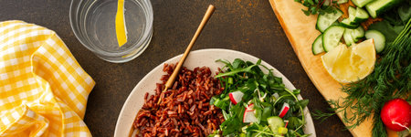 Delicious healthy breakfasts, chicken breast with red rice and salad mix with fresh seasonal organic vegetables and microgreens, top view of a plate with food and a cutting board with vegetables, bannerの写真素材