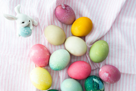 Multi-colored Easter eggs with decorative bunnies on a pink tablecloth, top view, Happy Easter holidayの写真素材