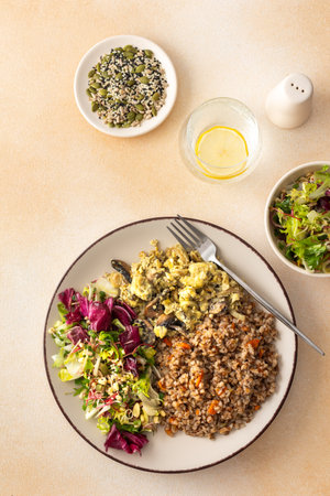 Delicious healthy breakfasts, buckwheat porridge with mixed salad with seeds and fried mushrooms with eggs, top view of plates with foodの写真素材