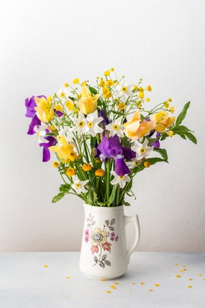 Home interior with a bouquet of spring flowers, Irises and yellow ranunculus, yellow tulips with white daffodilsの写真素材