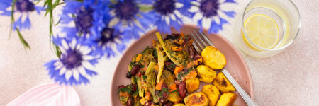 Stewed potatoes with stewed vegetables, broccoli and beans with carrots and herbs, a served table with food and a vase of flowers, a delicious hearty lunch or dinner, bannerの写真素材